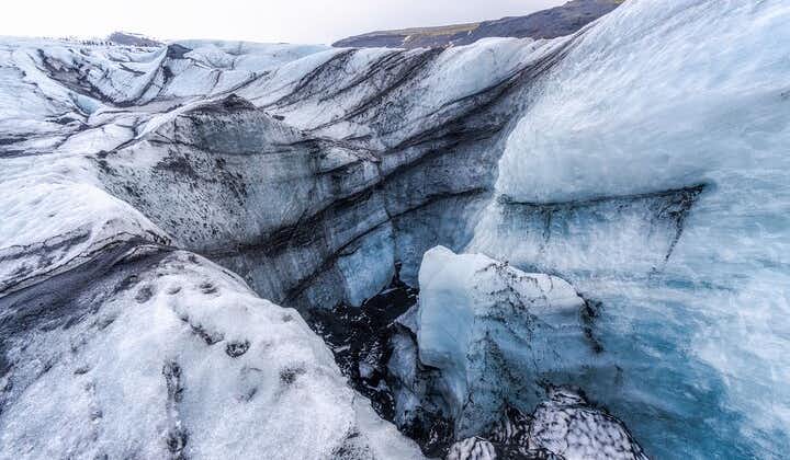 Vatnajokull Glacier ice formations are visible, showcasing a mix of striking blue ice and dark ash.