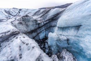 Vatnajokull Glacier ice formations are visible, showcasing a mix of striking blue ice and dark ash.