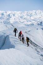 A group of four people walking up a slope on a glacier in Skaftafell nature reserve, Iceland.