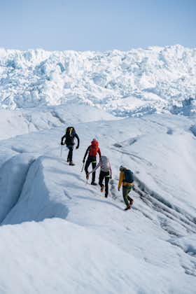 A group of four people walking up a slope on a glacier in the Skaftafell nature reserve, Iceland.