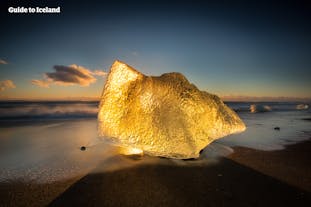 位于冰岛南岸钻石沙滩上的碎冰正在闪耀着金灿灿的光明