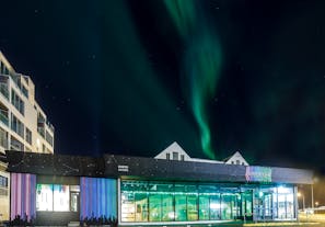 The northern lights cast a brilliant streak of color across the night sky above Aurora Reykjavik - The Northern Lights Center.