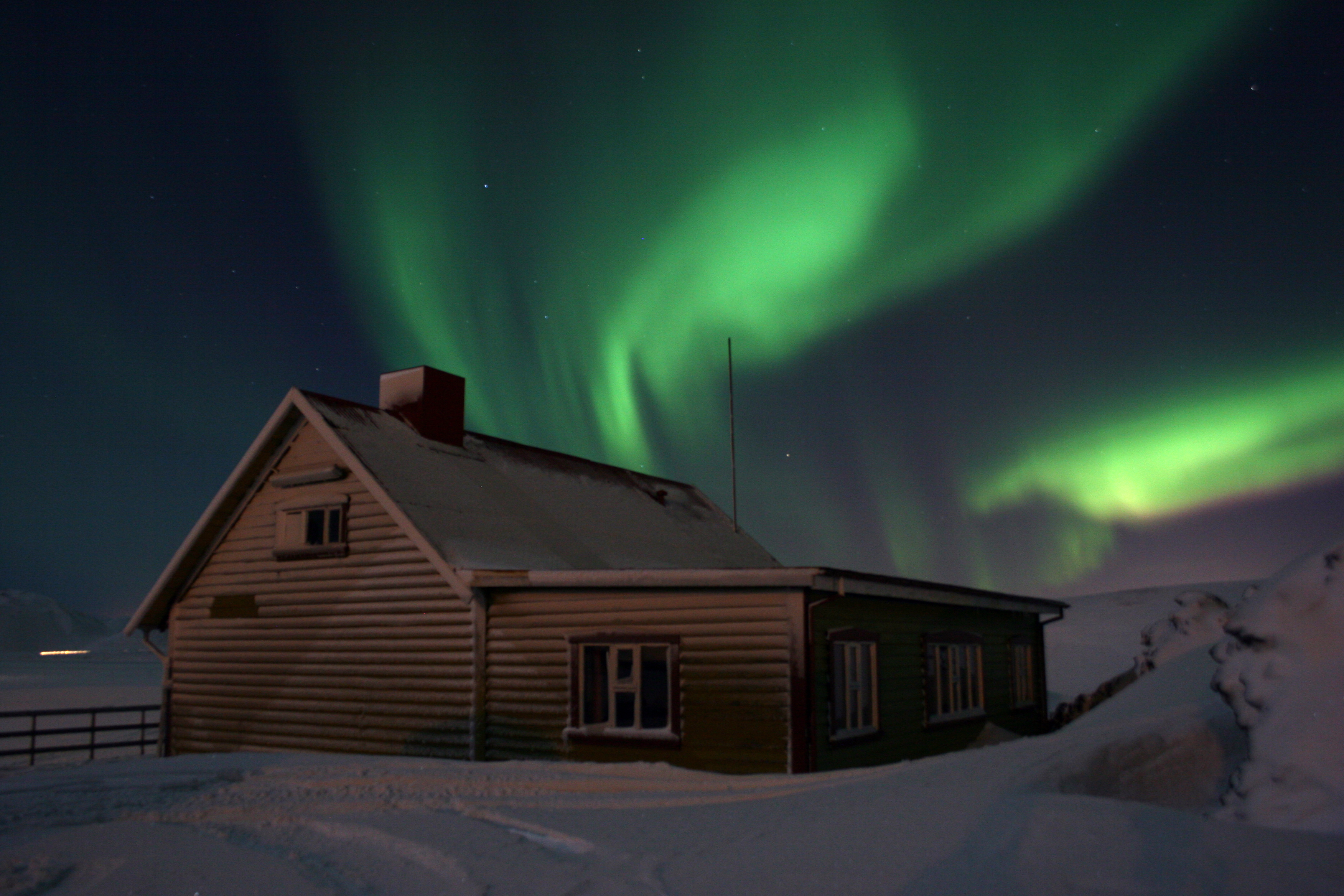 The aurora borealis dancing over a countryside cottage.