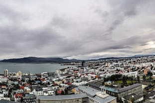 An aerial view of Reykjavik, its coastline, and a nearby mountain.