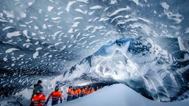 A guide leads travelers through an ice cave at Myrdalsjokull glacier.