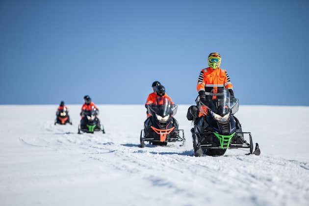 A group of people ride on snowmobiles on Myrdalsjokull on a glacier tour.