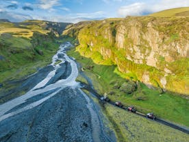A line of buggy drivers approach weaving streams on Iceland's South Coast, surrounded by rugged peaks.