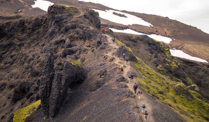 Hikers crossing a mountain ridge in the Icelandic Highlands.