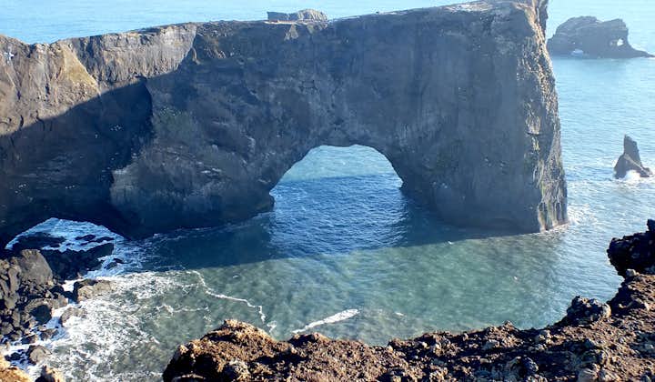 The massive rock arch at Dyrhólaey peninsula on the South Coast bathed in the summer sun's rays.