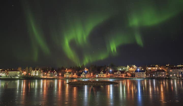 Aurora boreal sobre el estanque de la ciudad en Reikiavik