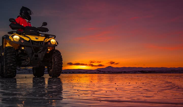A quad standing on the shores of Hafravatn in the midnight sun.