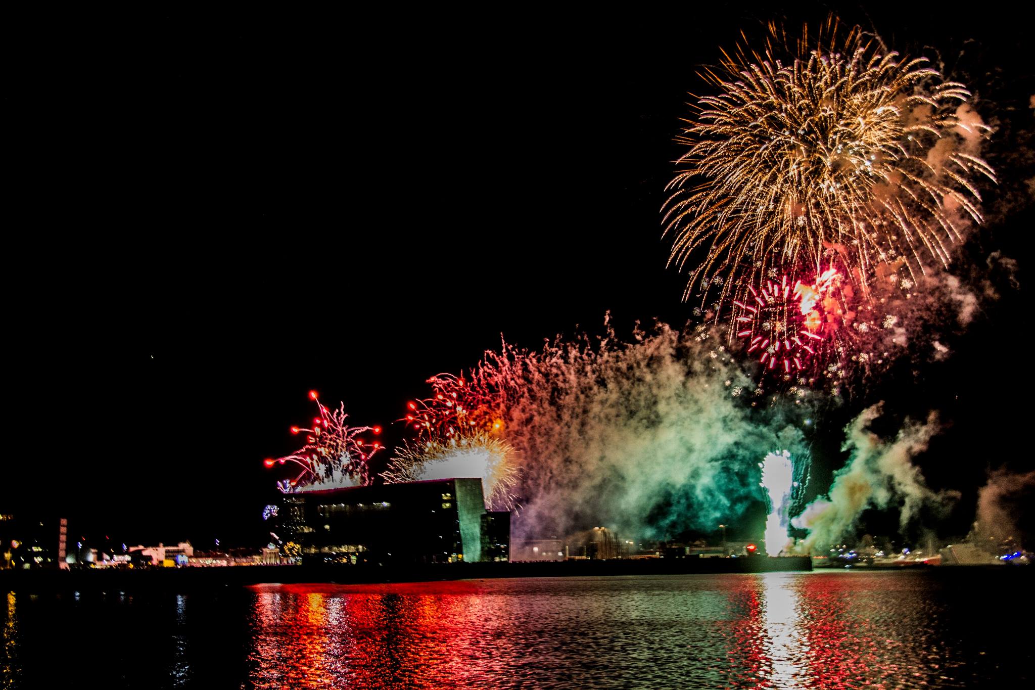 Fireworks during New Year's in Iceland casting their lights on Harpa Concert Hall.