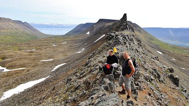 Hikers stand on a ridge in the Westfjords revealing spectacular summer views.