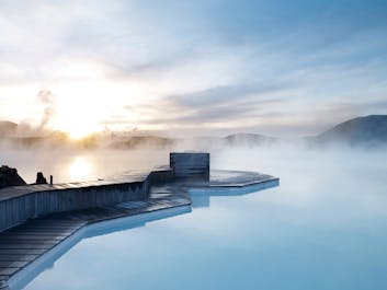 Damp stiger opp fra det asurblå vannet ved Den blå lagune, Islands mest populære basseng og spa.