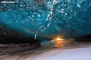 Promienie zimowego słońca przenikają przez piękny świat jednej z oszałamiających jaskiń lodowcowych Vatnajökull.