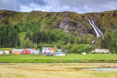 Kirkjubaejarklaustur village, with Systrafoss waterfall behind it during summer in Iceland.