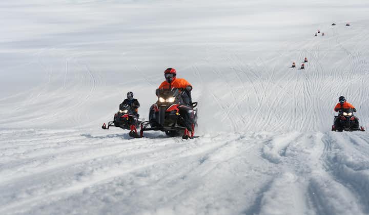 A group of snowmobilers riding across the snowy landscapes of Langjokull glacier.