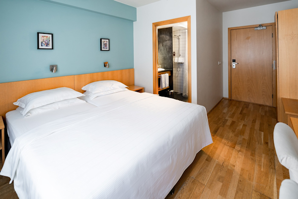 Two twin beds pushed together at a hotel room in Center Hotels Klopp, with a door leading to the ensuite bathroom.