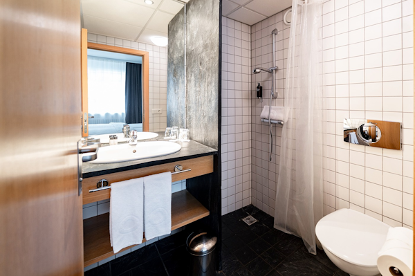 A bathroom in Center Hotels Klopp, with a sink, towels, and shower.