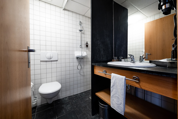 A bathroom at Center Hotels Klopp, featuring a shower, toilet, basin, and towel.