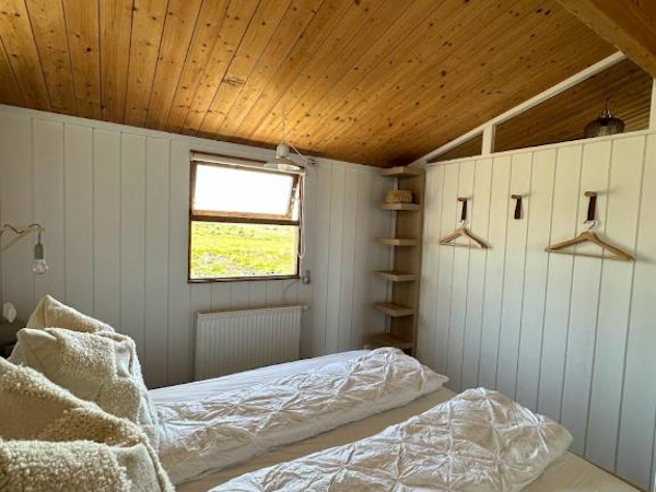 One of the bedrooms at Hestaland Horse Farm Cottage, featuring a double bed and coat hangers on the wall.