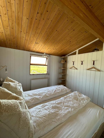 One of the bedrooms at Hestaland Horse Farm Cottage, featuring a double bed and coat hangers on the wall.
