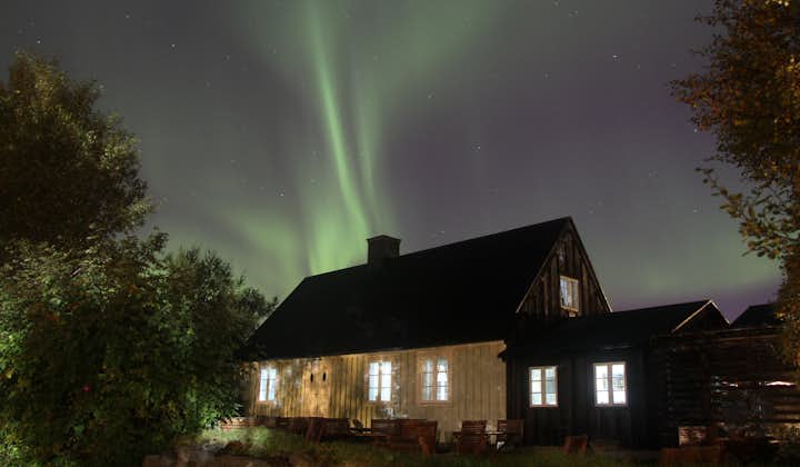 The aurora borealis dancing over a house in south Iceland in winter.