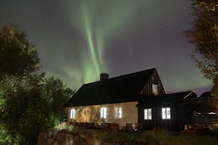 The aurora borealis dancing over a house in south Iceland in winter.