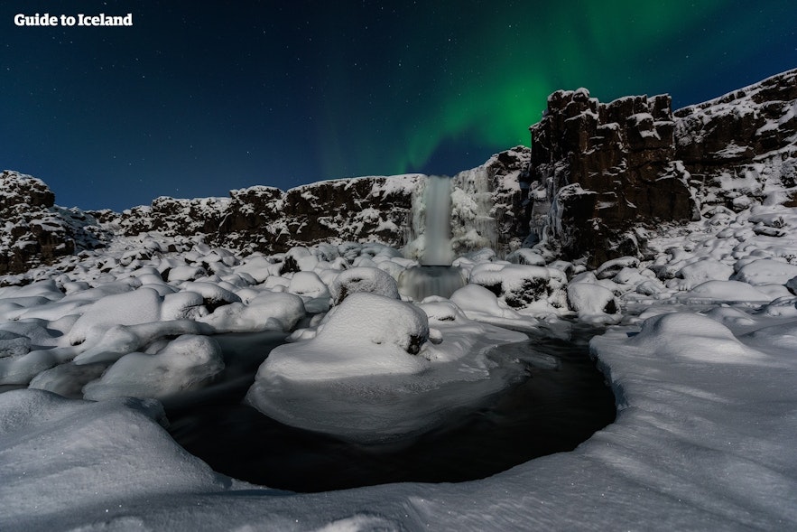 Öxaráfoss freezes solid during the winter; here, it is pictured beneath the aurora borealis.
