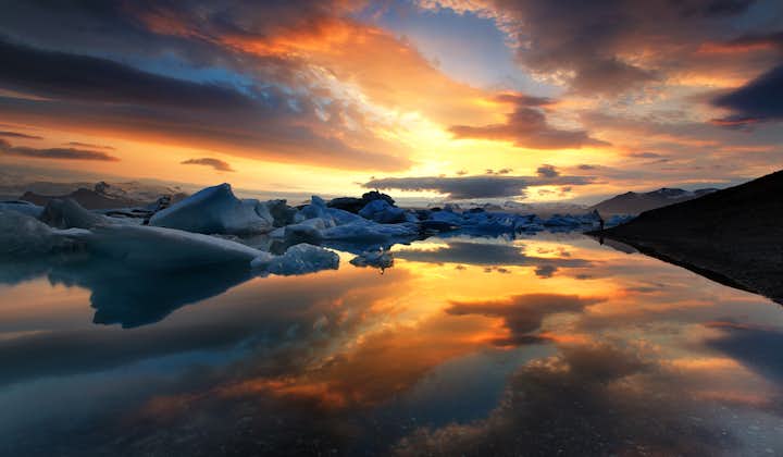 The colourful sky reflecting perfectly on the still surface of Iceland's deepest lake, Jökulsárlón glacier lagoon.