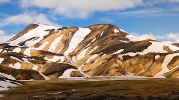 Streaks of snow lie across the caramel-colored peaks of Landmannalaugar on the Laugavegur trail in the Icelandic Highlands.