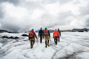 People on a private guided tour trek across the vast icy expanse of the Solheimajokull glacier.