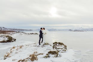 A couple enjoy an enchanting wedding ceremony at Thingvellir National Park surrounded by snow-covered landscapes.