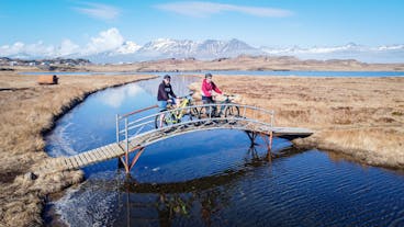 People stop on a picturesque footbridge with their bikes, enjoying the stunning surrounding scenery of Iceland's Eastfjords.