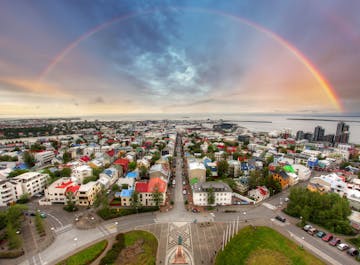 Een spectaculaire regenboog spant zich boven de kleurrijke daken van de stad Reykjavik, gezien vanaf de kerk Hallgrimskirkja.
