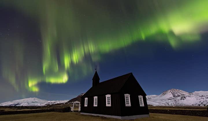 Las auroras boreales bailando sobre la iglesia de Búðakirkja en la península de Snæfellsnes en el oeste de Islandia.