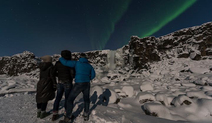 A group of travellers in Þingvellir National Park marvel over a display of the aurora borealis.