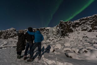 A group of travellers in Thingvellir National Park marvel over a display of the aurora borealis.