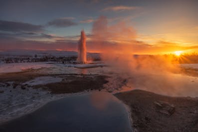 Potężny gejzer Strokkur wybucha, wyrzucając ogromne ilości wody wysoko w islandzkie zimowe niebo.