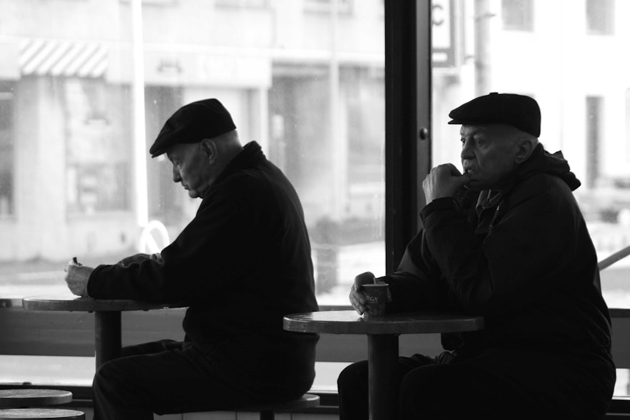 Dwóch dżentelmenów cieszących się ciepłą kawą na dworcu autobusowym Hlemmur.