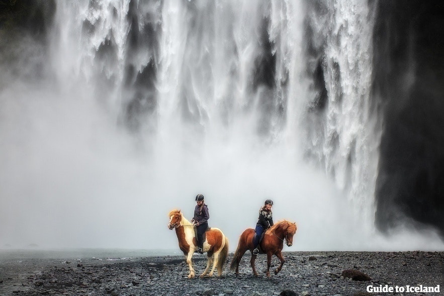 Riders in front of a waterfall on the south coast, leaving from Reykjavik, Iceland