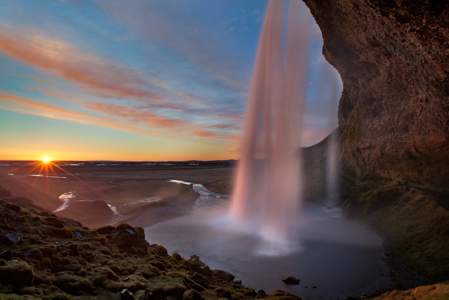 Blick von hinter dem herabstürzenden Wasser des Seljalandsfoss-Wasserfalls