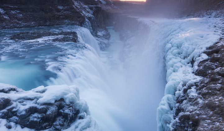 Chute d'eau de Gullfoss en hiver libérant des embruns glaciaux qui gèlent sur les roches et la mousse autour, créant une image dramatique de l'hiver.