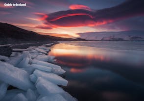 De rode avondhemel weerspiegeld in de serene gletsjerlagune Jökulsárlón.