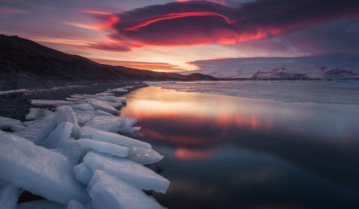 The red evening sky mirrored in the serene Jökulsárlón glacier lagoon.