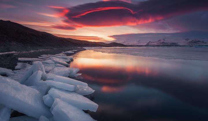 The red evening sky mirrored in the serene Jokulsarlon glacier lagoon.