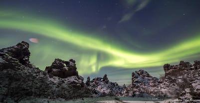 A swathe of the northern lights in the sky over some rugged rock formations in Iceland.