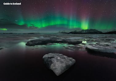 绿色、粉色与紫色交织的北极光在杰古沙龙冰河湖上方舞动