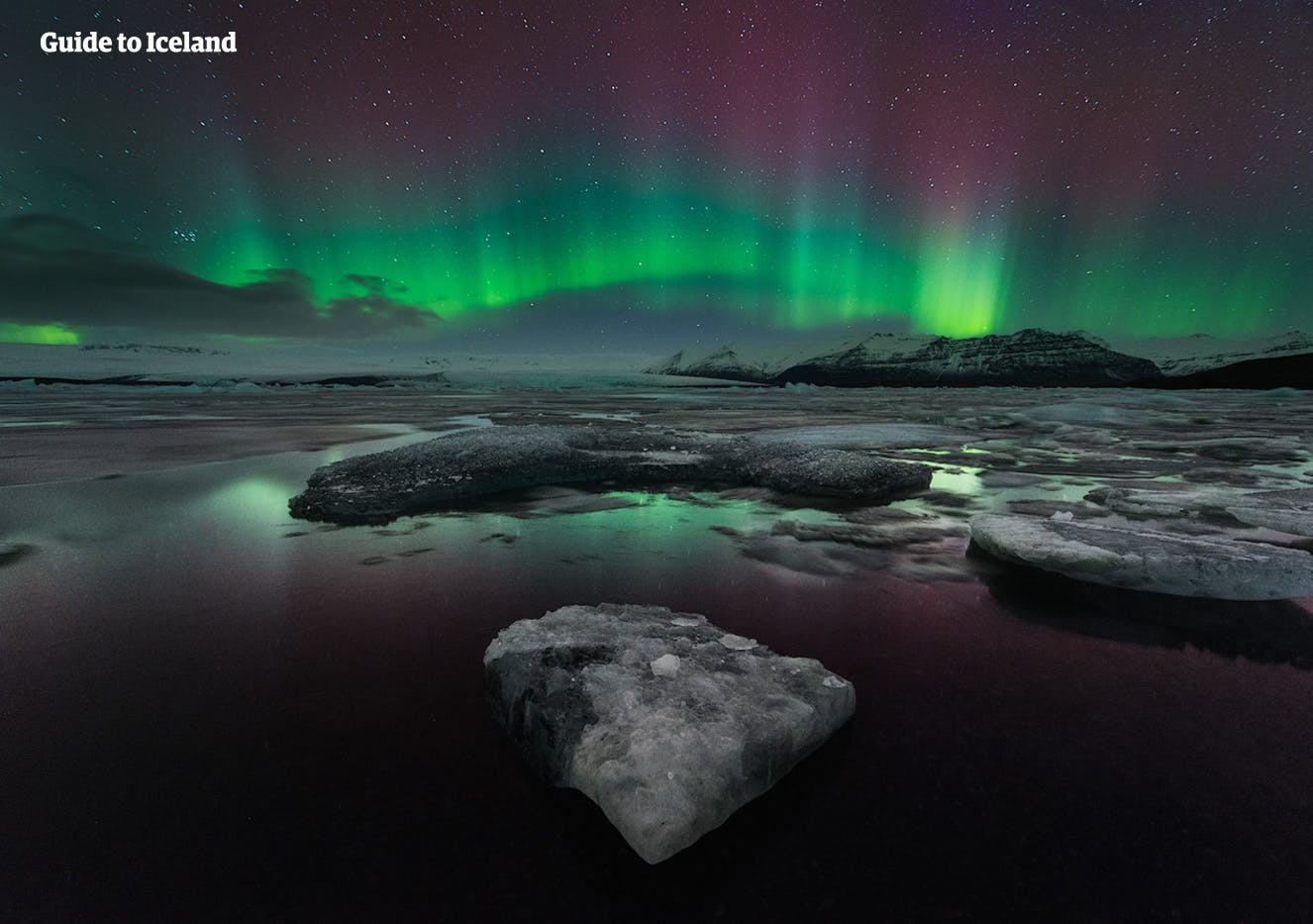 绿色、粉色与紫色交织的北极光在杰古沙龙冰河湖上方舞动
