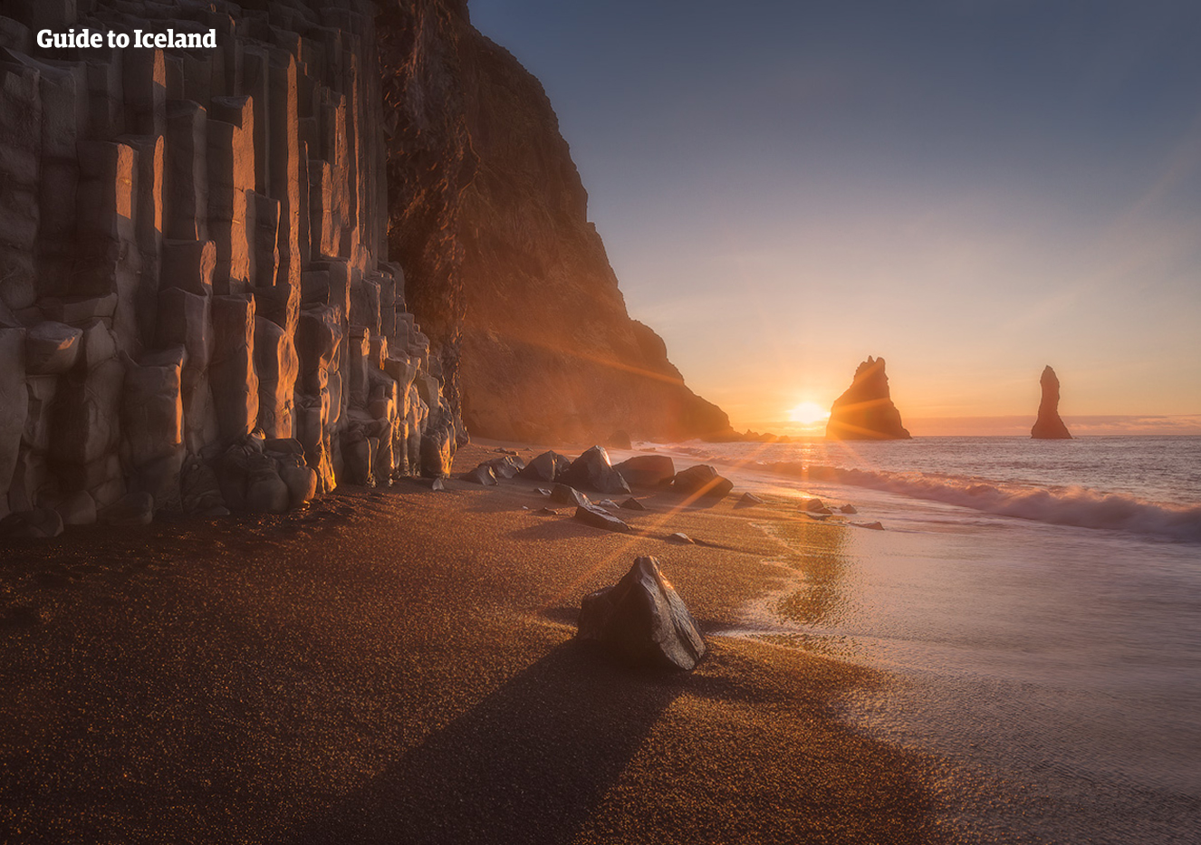 พระอาทิตย์ส่องแสงบนหาดทรายดำเรย์นิสฟยาราซึ่งอยู่ริมผาเสาหินบะซอลต์หกเหลี่ยม